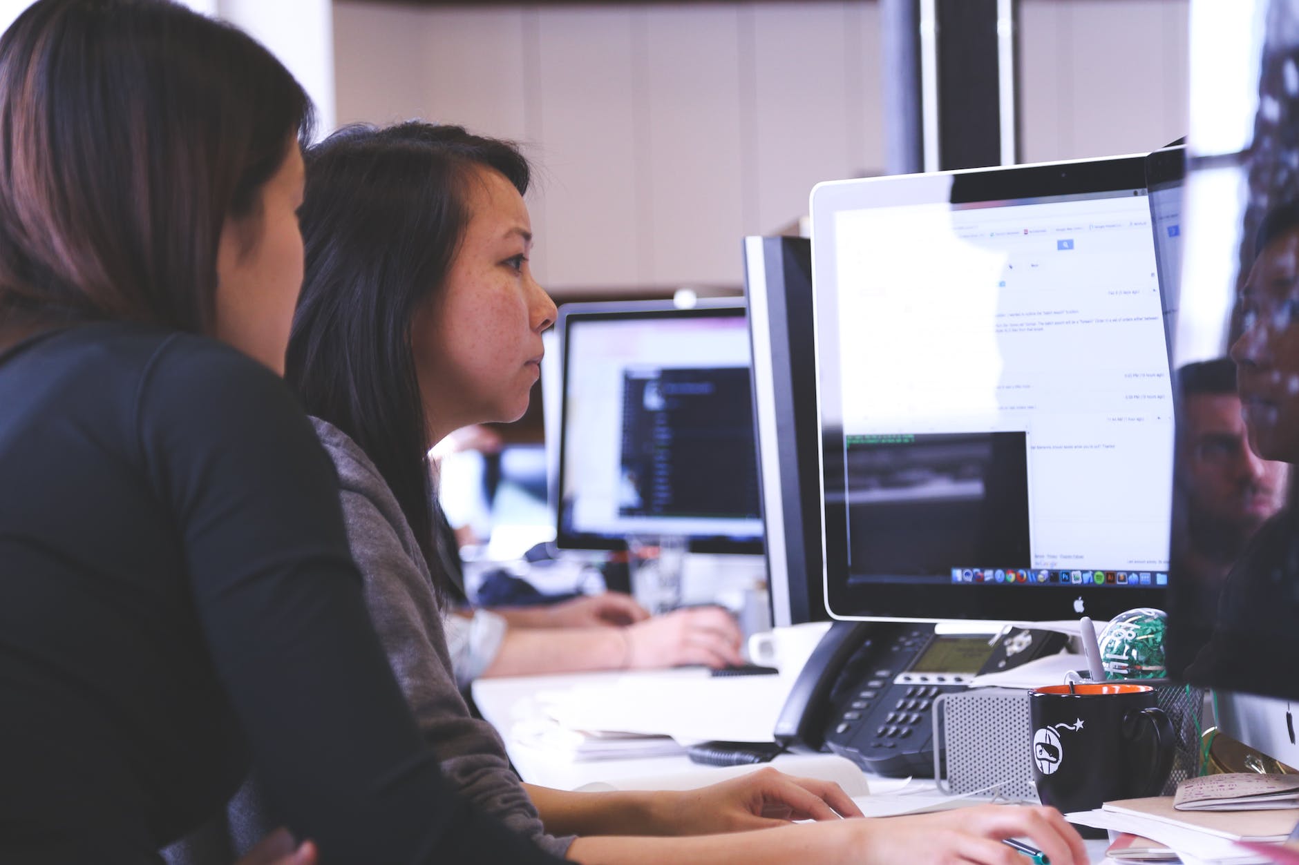 two women sitting in front of computer monitor